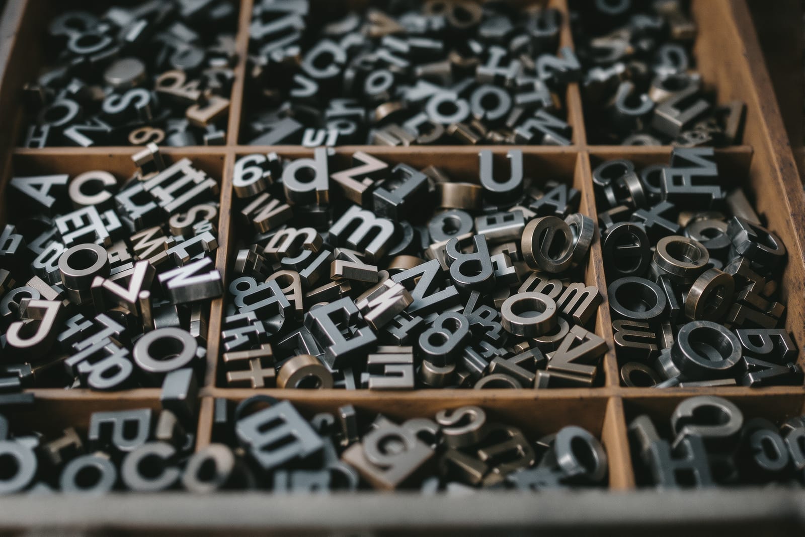 A compartmented case of metal letterpress type sorts in mixed alphabets under raking light