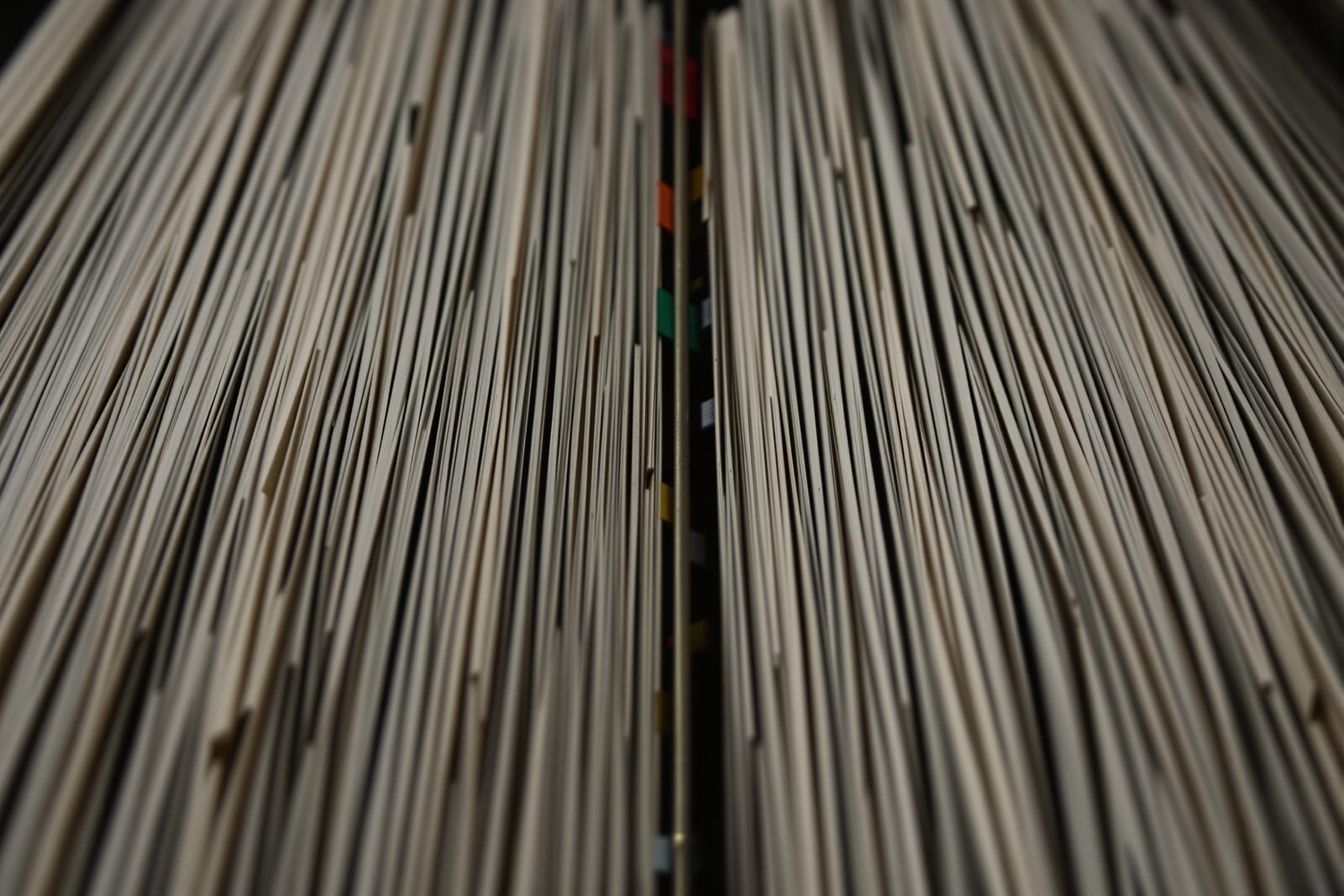 A dense two-column encyclopaedia spread seen at a steep angle with coloured tabs marking cross-references